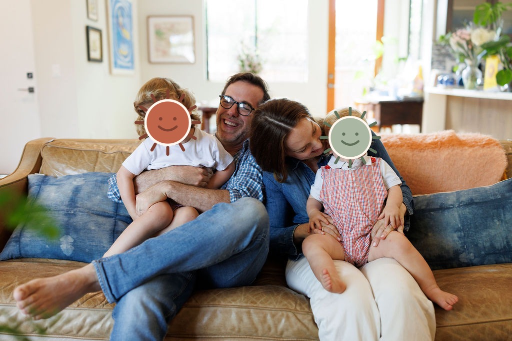 Michael and Hadley laughing on the couch with Henry and Luke, whose faces are covered by illustrated stickers for privacy.